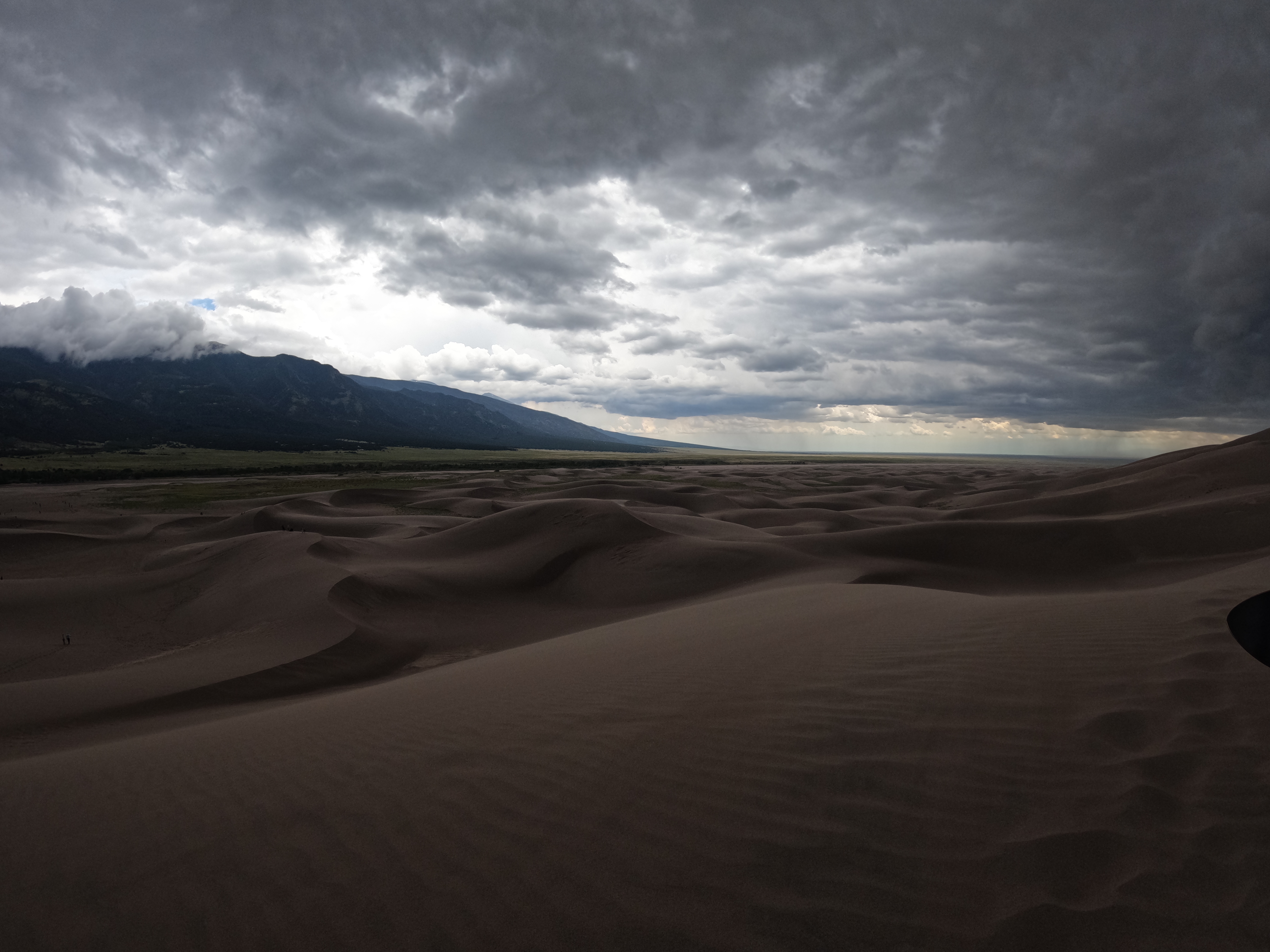 a panoramic view of sand dunes under a cloudy sky